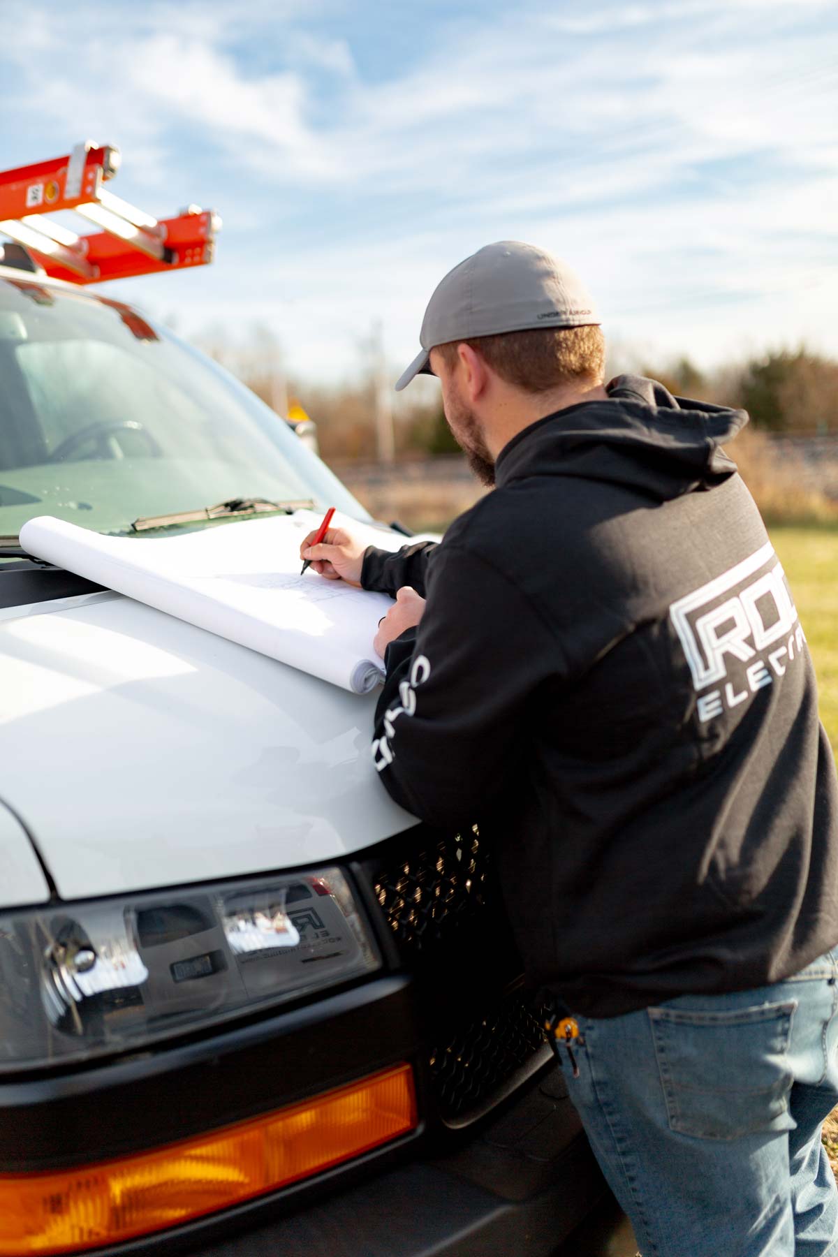 roc team member marking up blueprint on hood of van